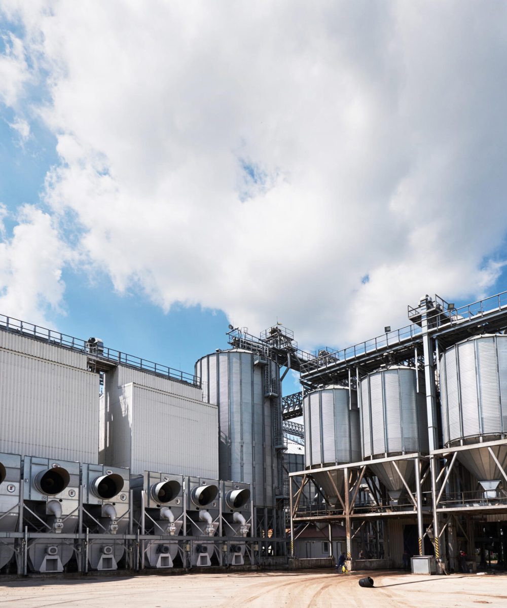 Agricultural Silos. Building Exterior. Storage and drying of grains, wheat, corn, soy, sunflower against the blue sky with white clouds.